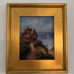 painting of house and the sea set in gold frame