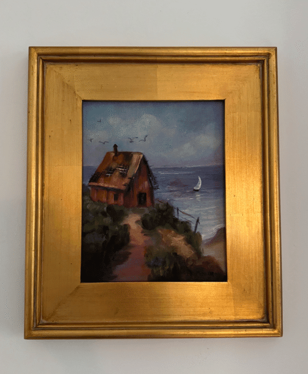 painting of house and the sea set in gold frame